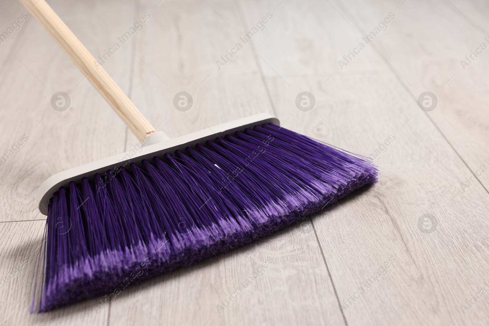 Photo of Sweeping wooden floor with bright broom indoors