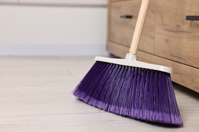 Photo of Sweeping wooden floor with bright broom indoors