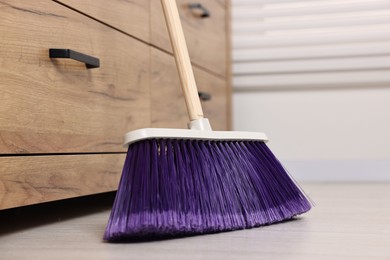 Photo of Sweeping wooden floor with bright broom indoors