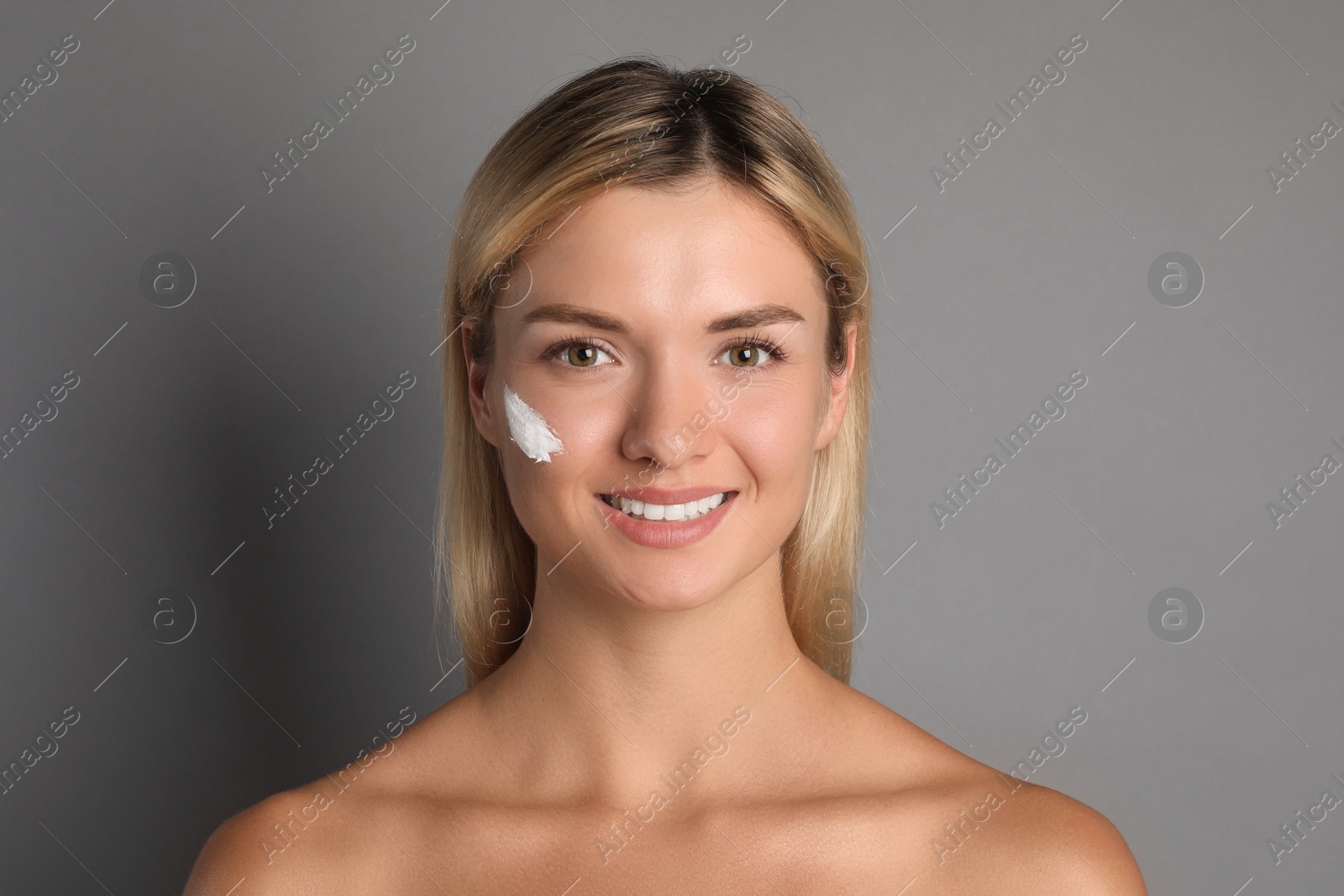 Photo of Beautiful woman with cream on her face against grey background