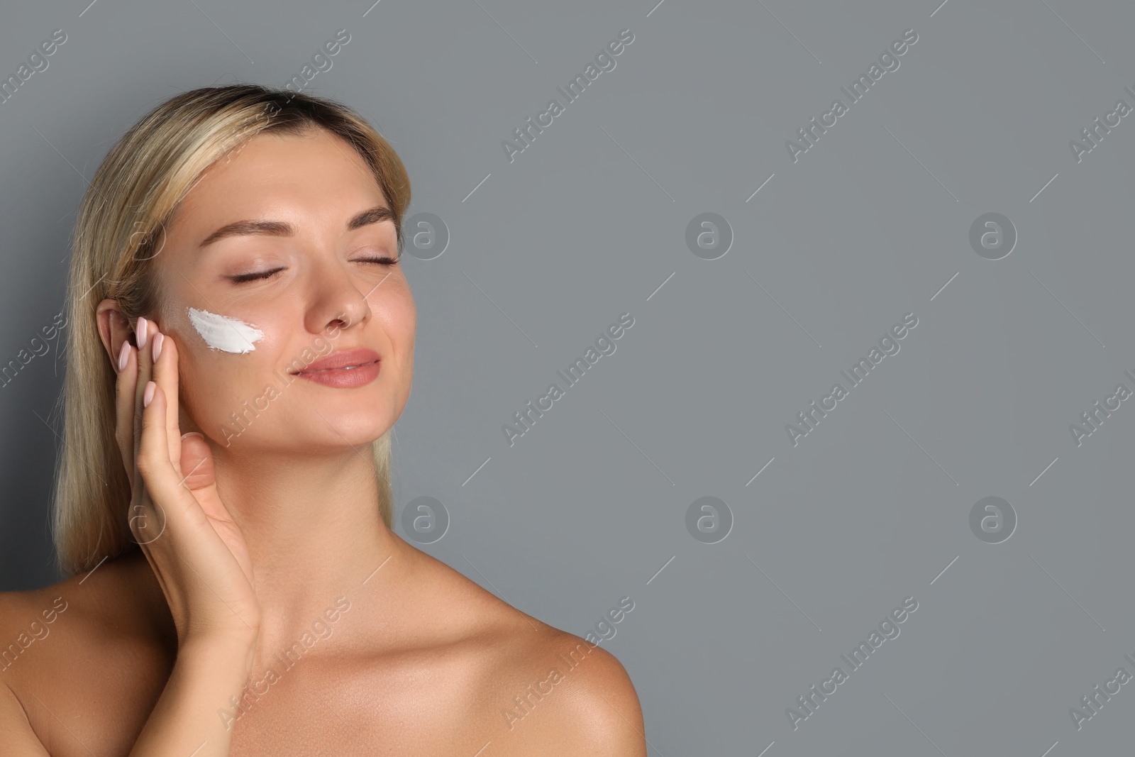 Photo of Beautiful woman with cream on her face against grey background, space for text