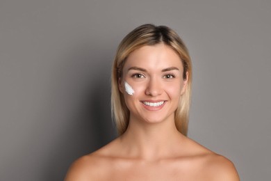 Photo of Beautiful woman with cream on her face against grey background