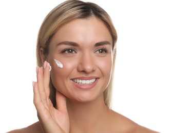 Beautiful woman applying face cream on white background