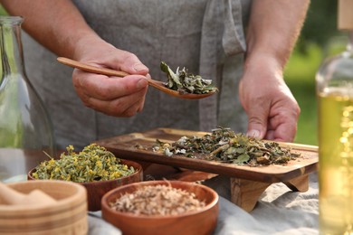 Photo of Senior woman making tincture at table outdoors, closeup