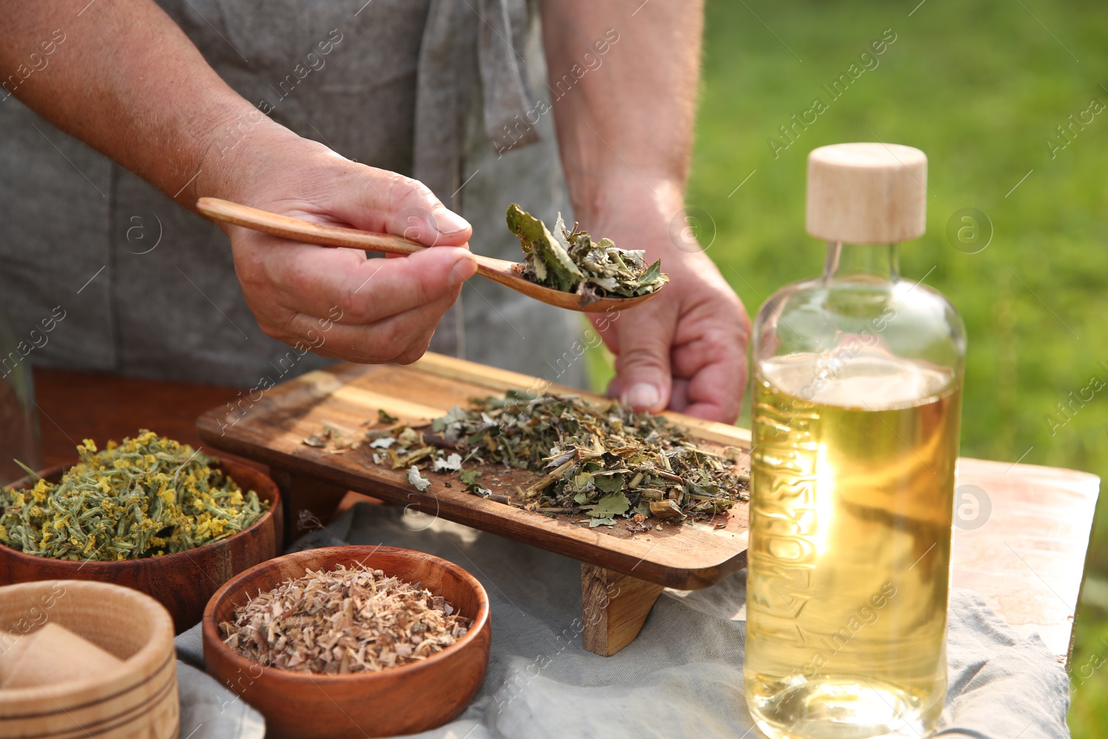 Photo of Senior woman making tincture at table outdoors, closeup