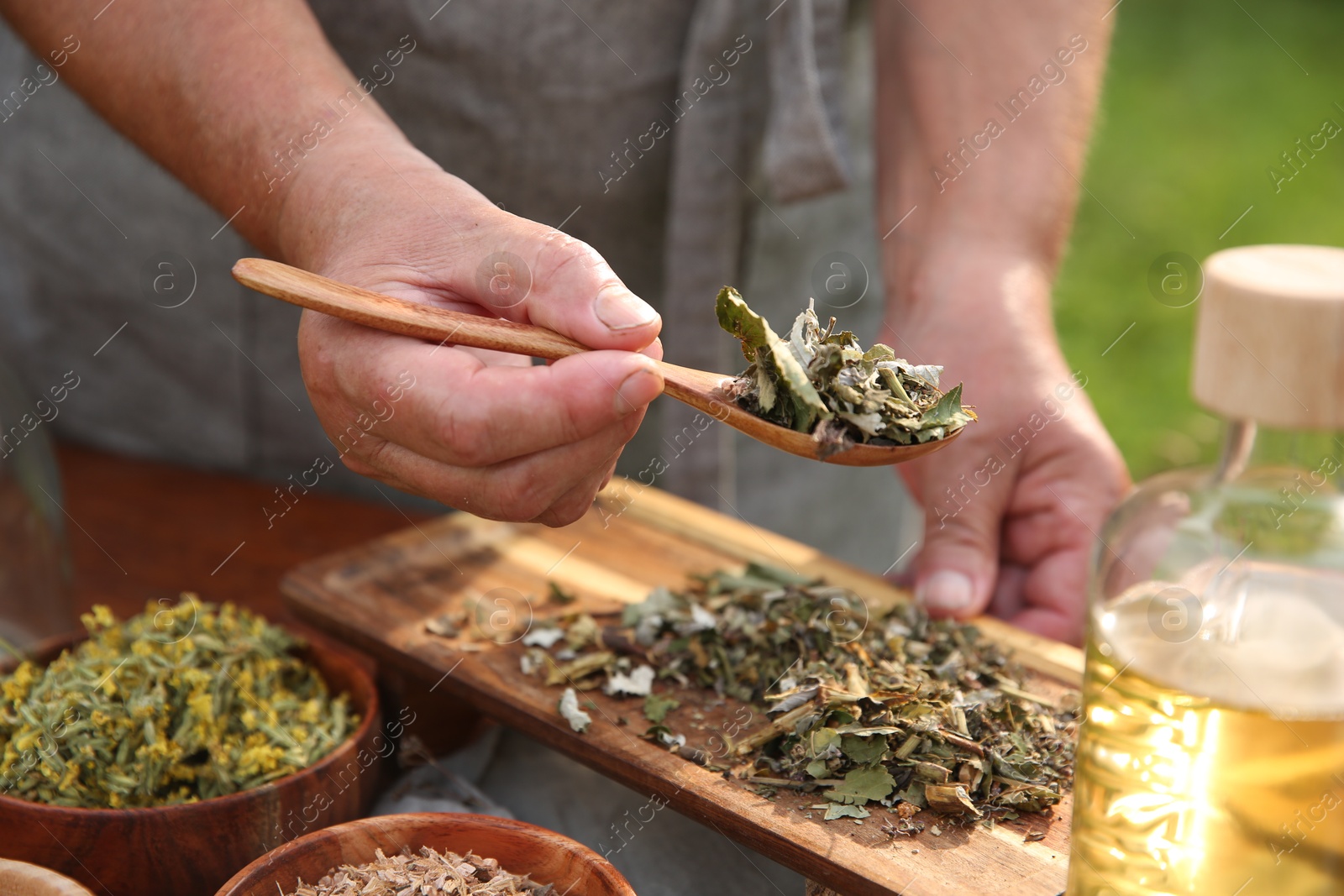 Photo of Senior woman making tincture at table outdoors, closeup