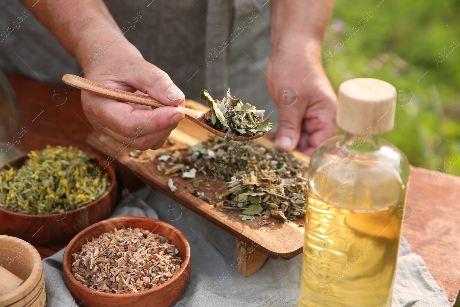 Photo of Senior woman making tincture at table outdoors, closeup