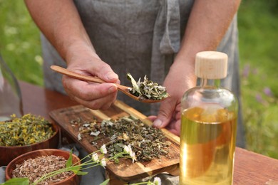 Photo of Senior woman making tincture at table outdoors, closeup