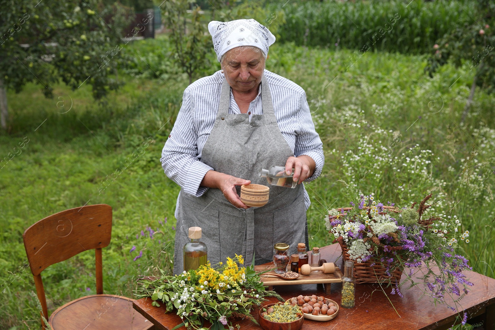 Photo of Senior woman making tincture at table outdoors