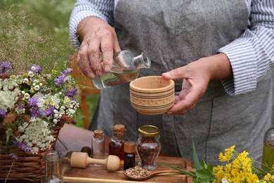 Photo of Senior woman making tincture at table outdoors, closeup