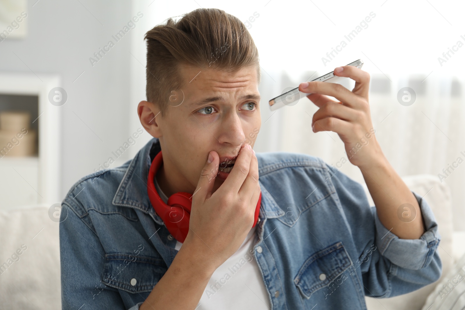 Photo of Young man with smartphone listening to voice message at home