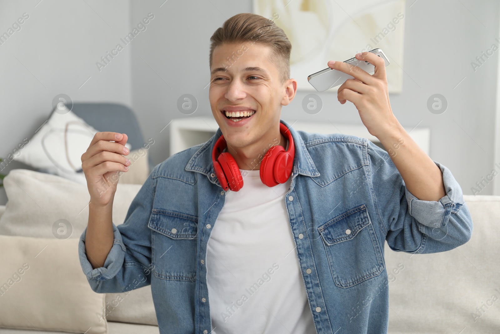 Photo of Young man with smartphone listening to voice message at home