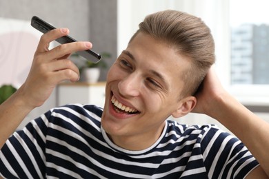 Photo of Young man with smartphone listening to voice message at home