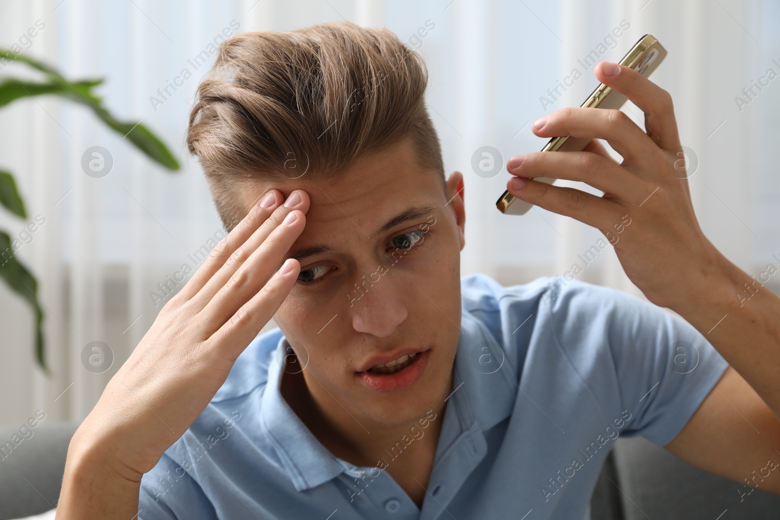 Photo of Young man with smartphone listening to voice message at home