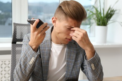 Photo of Young man with smartphone listening to voice message in office