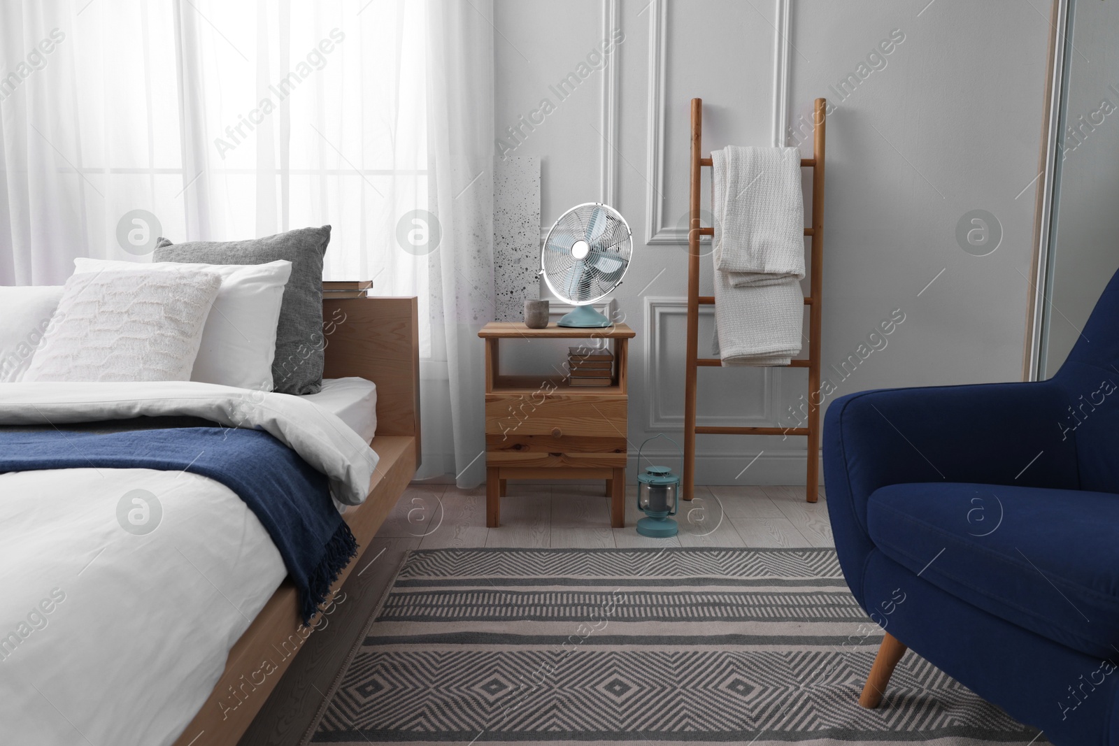 Photo of Stylish living room interior with bed, bedside table and fan