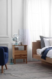 Photo of Stylish living room interior with bed, bedside table and fan