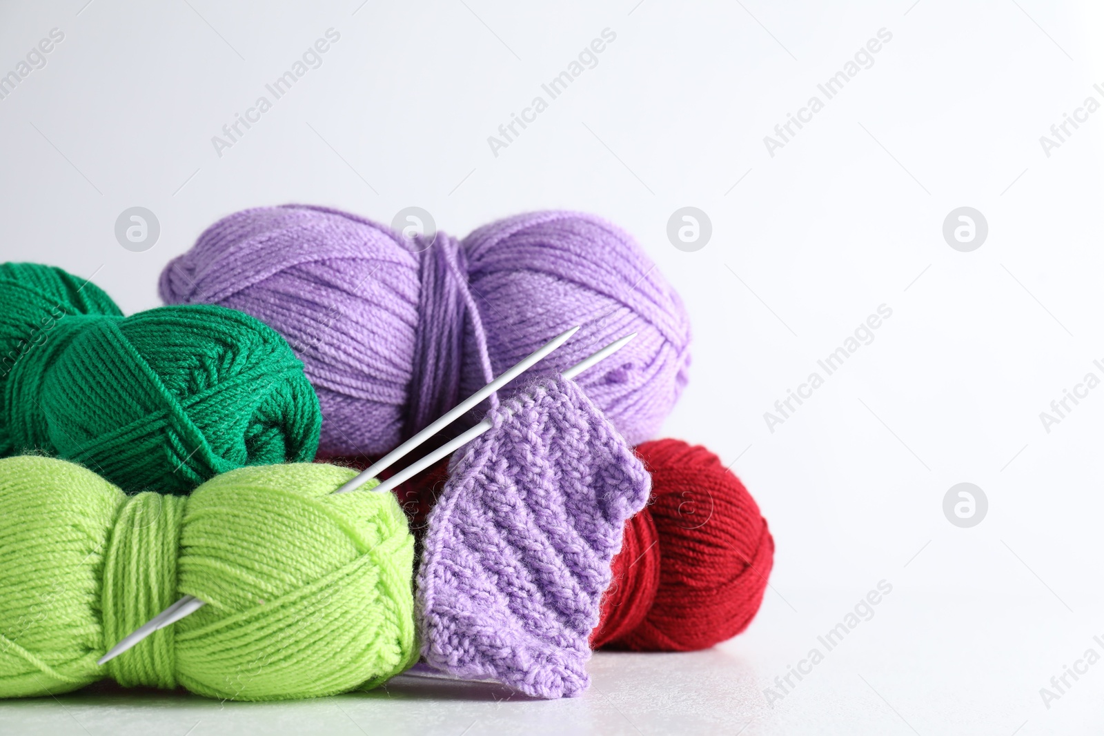 Photo of Many soft skeins of yarn on light grey background, space for text