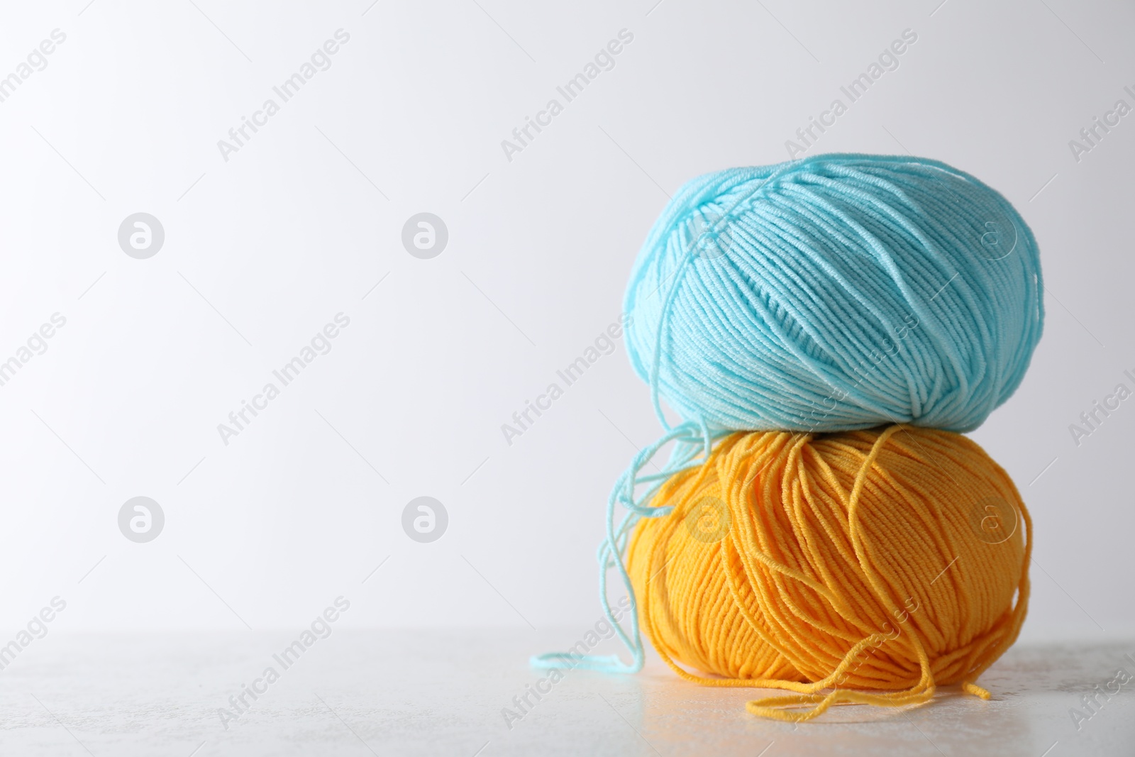 Photo of Two soft skeins of yarn on light grey background, space for text