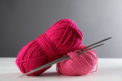 Two soft skeins of yarn on white table against grey background