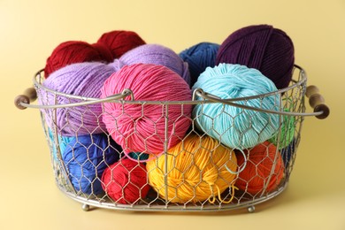 Metal basket with bright yarns on yellow background, closeup