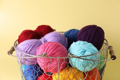 Metal basket with bright yarns on yellow background, closeup