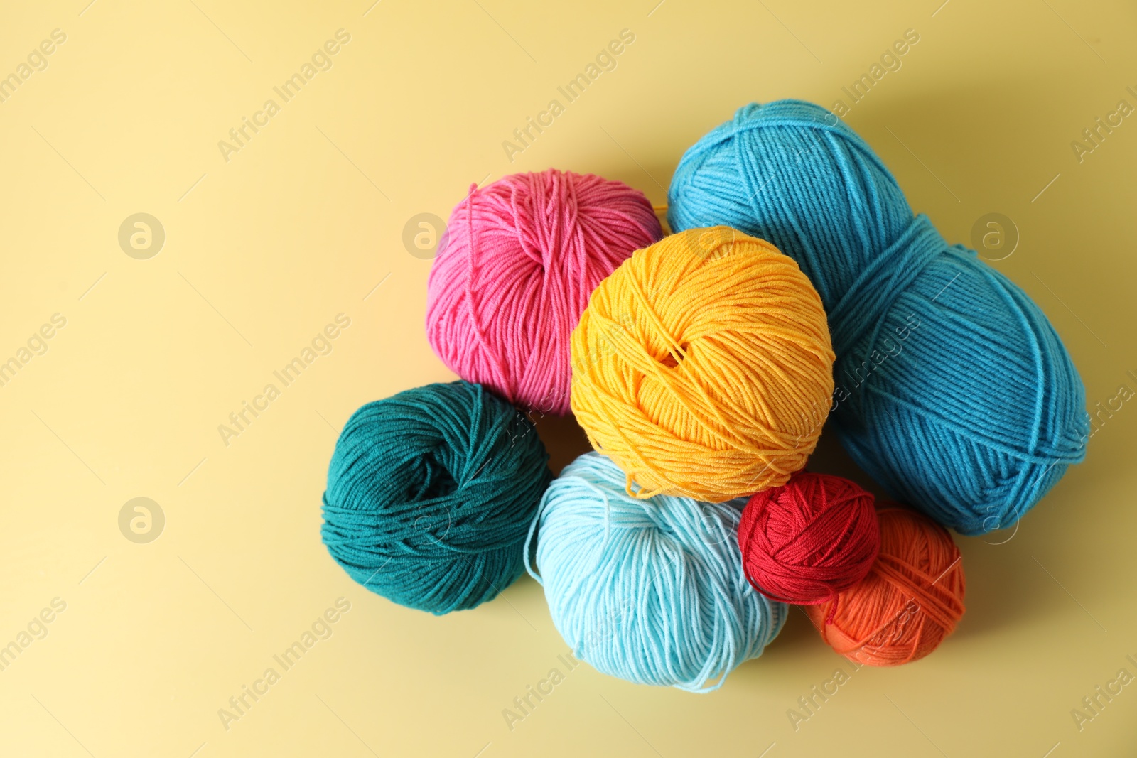 Photo of Many different yarns on yellow background, flat lay. Space for text