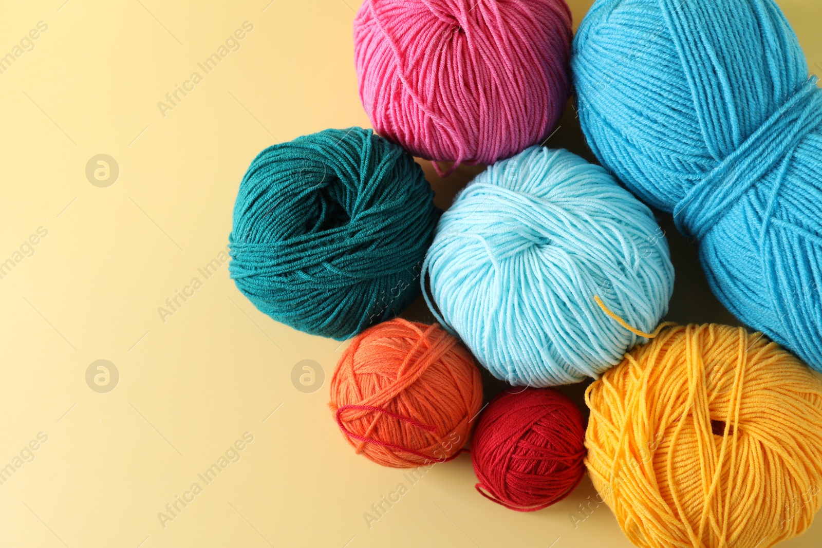 Photo of Many different yarns on yellow background, flat lay. Space for text