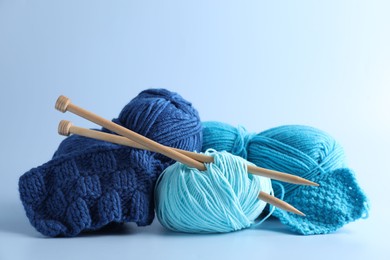 Different yarns, knitting needles and pattern samples on light background