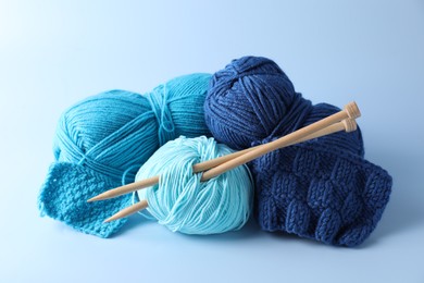 Different yarns, knitting needles and pattern samples on light background