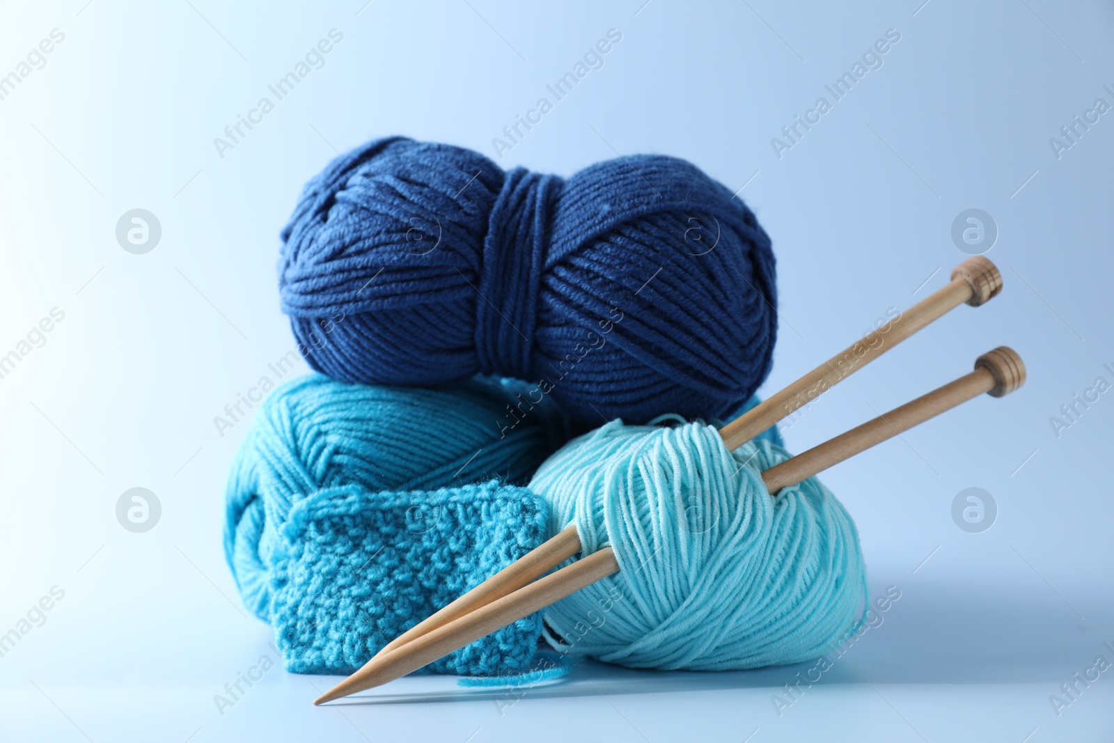 Photo of Different yarns, knitting needles and pattern sample on light background