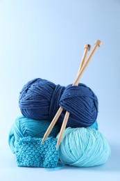 Different yarns, knitting needles and pattern sample on light background