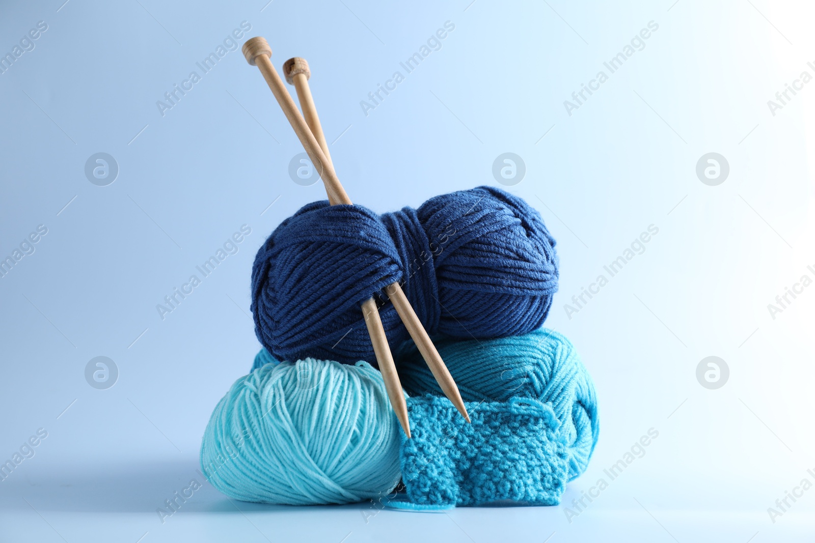 Photo of Different yarns, knitting needles and pattern sample on light background