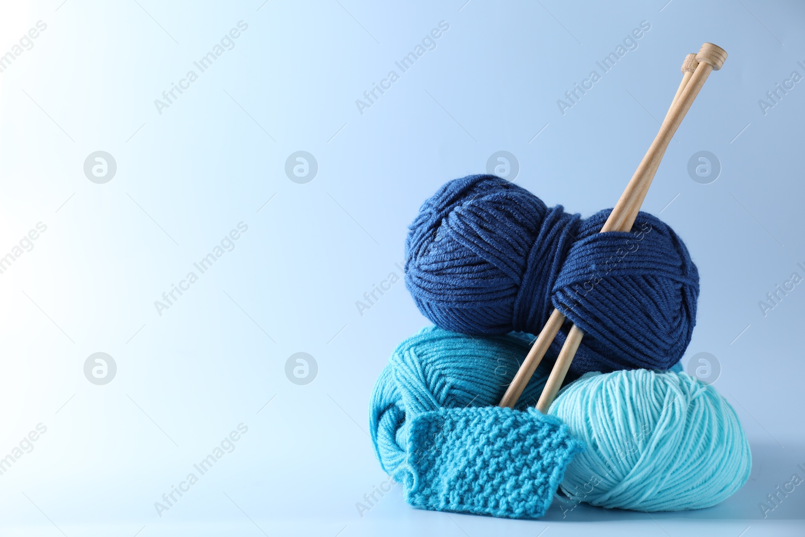 Photo of Different yarns, knitting needles and pattern sample on light background. Space for text