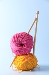 Colorful yarns and knitting needles on light background