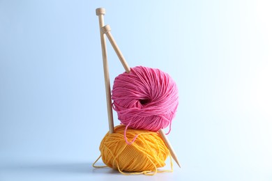 Colorful yarns and knitting needles on light background