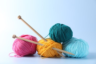 Colorful yarns and knitting needles on light background