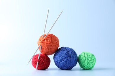 Colorful yarns and knitting needles on light background