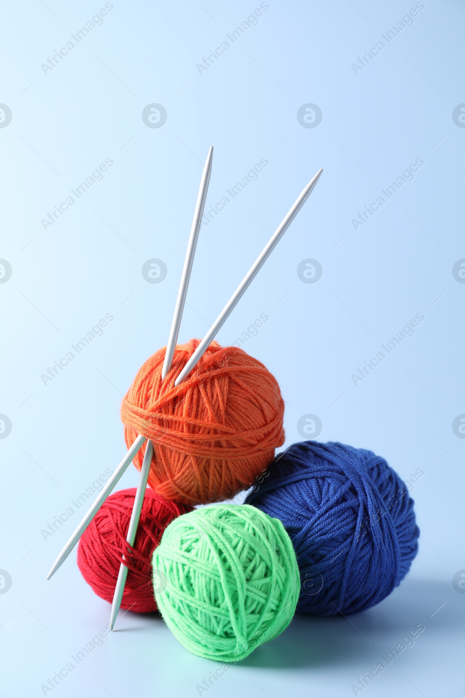 Photo of Colorful yarns and knitting needles on light background