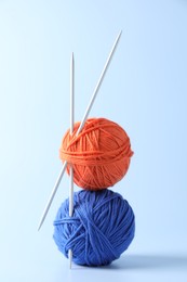 Colorful yarns and knitting needles on light background