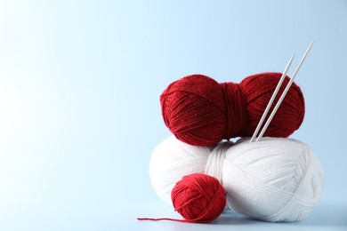 Colorful yarns and knitting needles on light background. Space for text