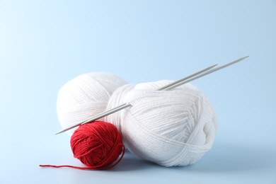 Colorful yarns and knitting needles on light background