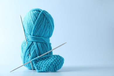 Skein of yarn, knitting needles and pattern sample on light background. Space for text