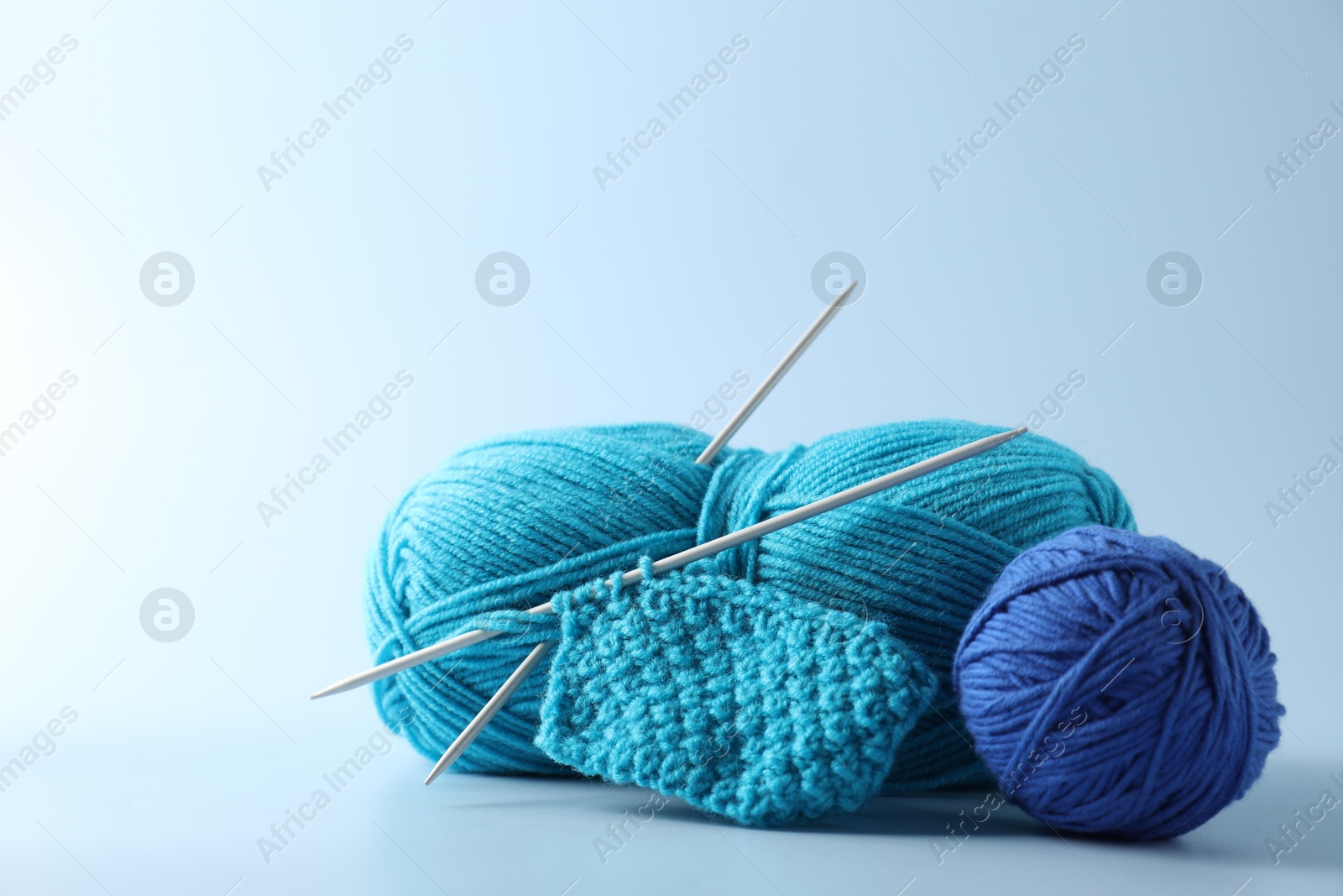 Photo of Colorful yarns, knitting needles and pattern sample on light background. Space for text