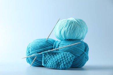 Colorful yarns, knitting needles and pattern sample on light background