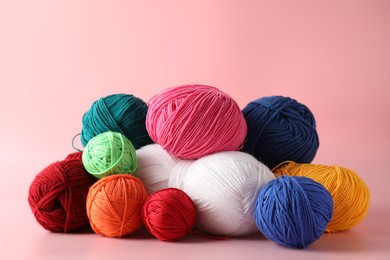 Pile of different colorful yarns on pink background