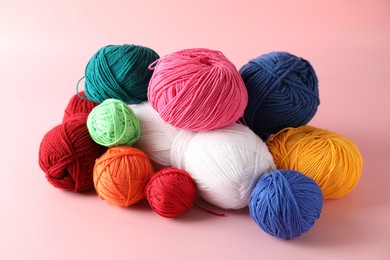 Pile of different colorful yarns on pink background