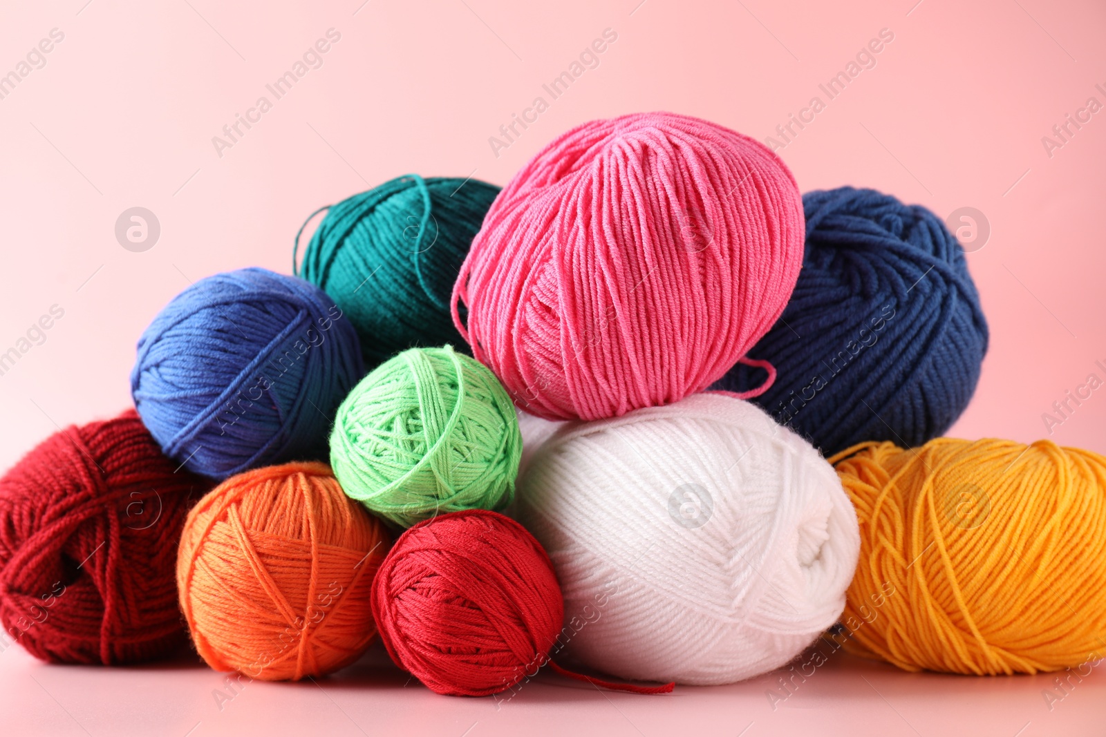 Photo of Pile of different colorful yarns on pink background, closeup