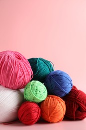 Pile of different colorful yarns on pink background, closeup. Space for text