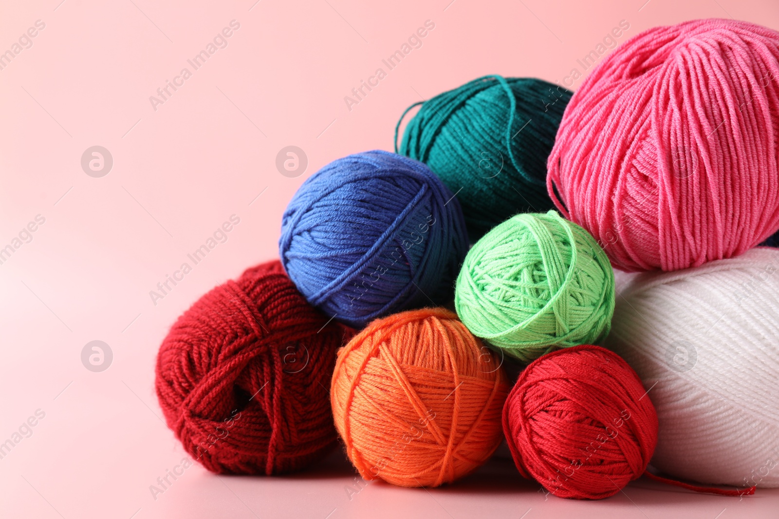 Photo of Pile of different colorful yarns on pink background, closeup. Space for text